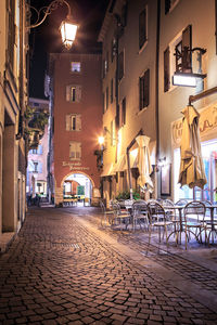 Empty alley amidst buildings in city at night