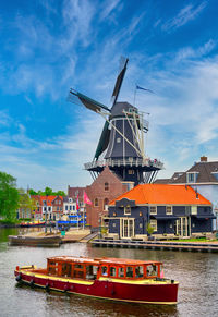 Traditional windmill in river against sky