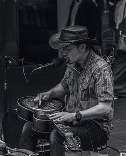 Midsection of man playing guitar at music concert