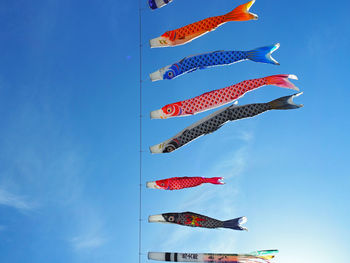 Low angle view of colorful balloons against blue sky