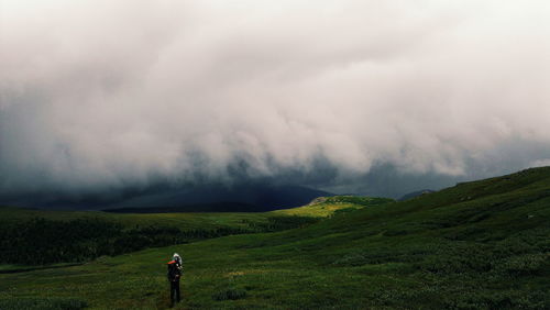 Rear view of woman standing on landscape against sky