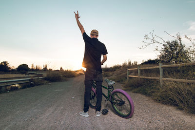 Man riding bicycle on road against sky