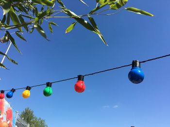Low angle view of hanging lights against blue sky