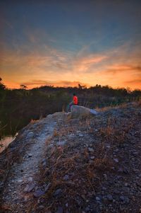 Person on field against sky during sunset