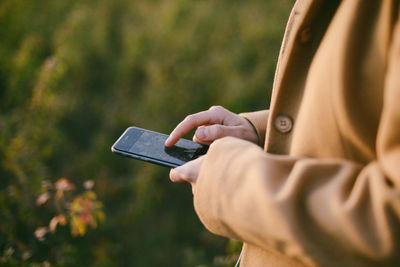 Midsection of woman using phone while standing outdoors