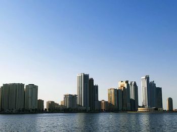 Sea by modern buildings against clear sky