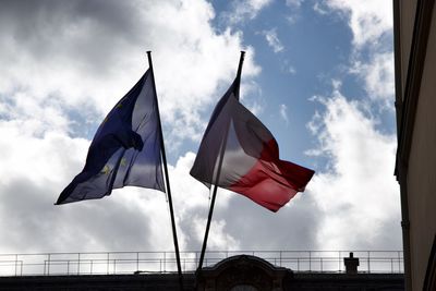 Low angle view of flags against cloudy sky