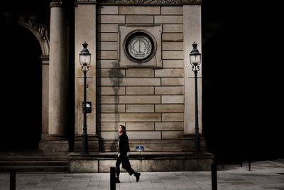 Side view of man walking on street against building