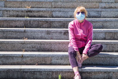 Woman with medical mask doing gymnastics in the city, new normal concept