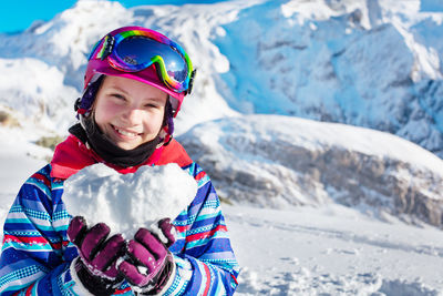 Portrait of girl holding heart shape made of snow