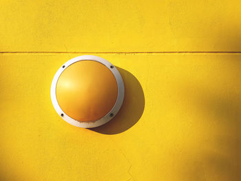 Round yellow light luminaire fixture on vivid yellow wall background