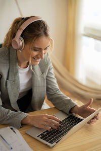 Young woman working at home with laptop on desk and headphones.  notebook for working. 