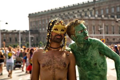 Shirtless men with body paint and eye mask during carnival
