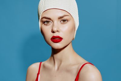 Close-up portrait of young woman with eyes closed against blue background