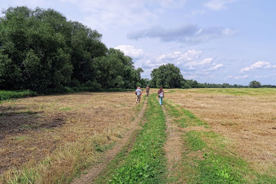 People walking on field against sky