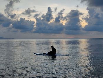 Silhouette man on boat in sea against sky during sunset