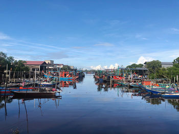 Boats moored in canal against sky in city