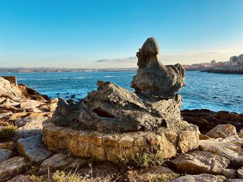 Rock formation on beach against sky