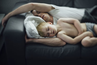 High angle view of father and son sleeping on sofa at home