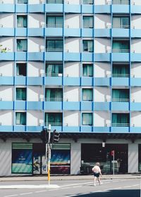 Rear view of woman walking on street against buildings in city