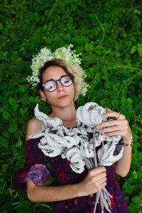 Directly above shot of woman holding flowers while lying on land