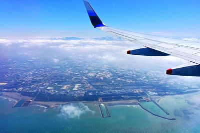 Airplane flying over cityscape against sky