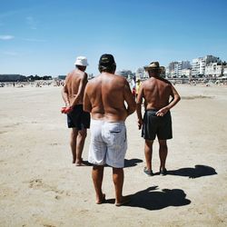 Rear view of men standing on beach