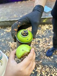 Close-up of hand holding fruit. comparing apple green to a spraycan. 