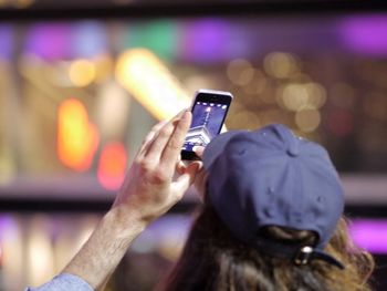 Rear view of man taking pictures on mobile phone