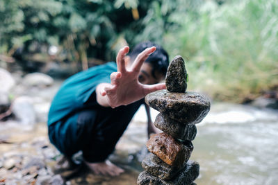 A boy stacking stones by the river