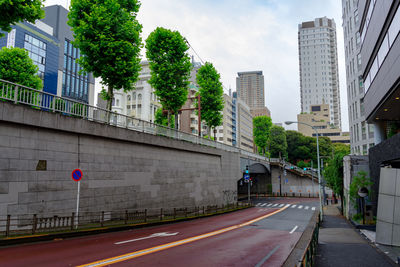Road by buildings against sky in city