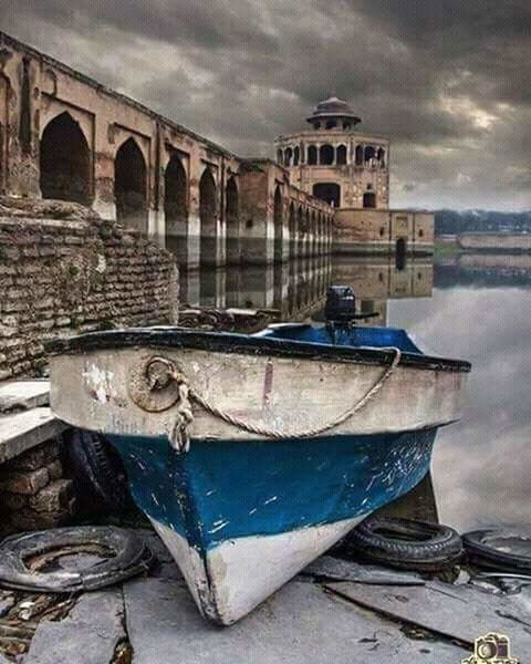 built structure, architecture, nautical vessel, boat, moored, building exterior, transportation, mode of transport, cloud - sky, sky, history, harbor, cloudy, outdoors, the past, cloud, water, architectural column, obsolete, no people, day, fishing boat, shore, in front of, historic