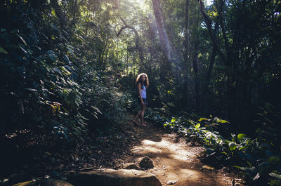 Woman standing by tree in forest