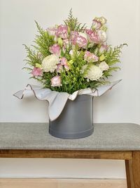 Flower vase on table against white wall