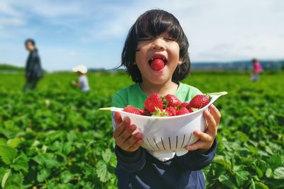 Happy girl holding fruit while standing outdoors