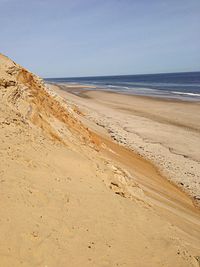 Sand dune at beach against sky