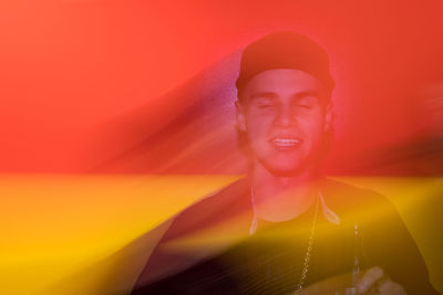 Smiling young woman standing against red wall