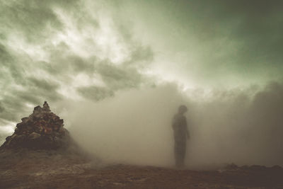 Man standing on rock against sky