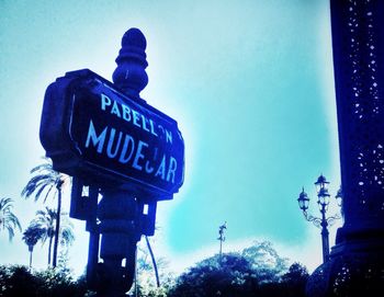 Low angle view of signboard against blue sky