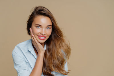 Portrait of young woman standing against gray background