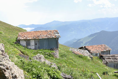 House on field by mountain against sky