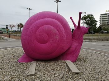 Close-up of pink umbrella on road against sky