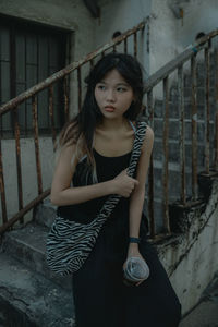 Portrait of young woman standing by railing