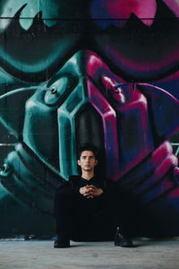 Full length portrait of young man sitting outdoors