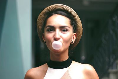 Portrait of young woman blowing bubble gum
