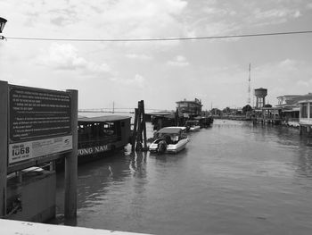 Boats moored on river in city against sky