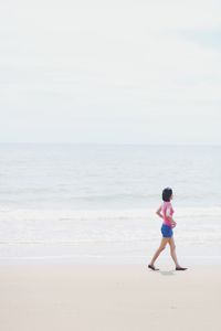 Side view of teenage girl walking at sea shore