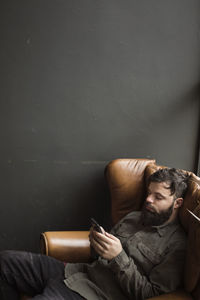 Man relaxing on sofa against wall