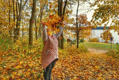 Woman with autumn leaves in forest