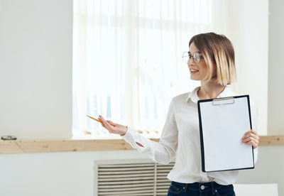 Side view of young woman standing against wall